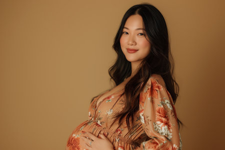 pregnant Asian woman in dress on beige background.の素材