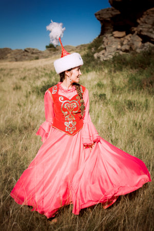 Beautiful woman in a dress and hat on the nature Kazakh woman and man in national costumesの写真素材