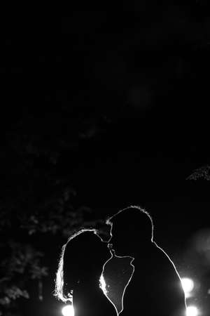 Young couple enjoying time in the forest during nighttime. Silhouette picture of the couple looking at each other in the forest with backlight.の写真素材