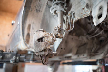 The car lifted on a lift, car suspension covered with rust, brake caliper change.  Auto service industry.の写真素材
