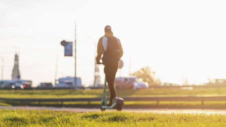 Blurred image of Young man riding an e-scooter in city traffic. Electric scooter new way city mobility. Green transportation. Sustainable climate neutral cities goals. Green mobility sustainable transportation.の写真素材