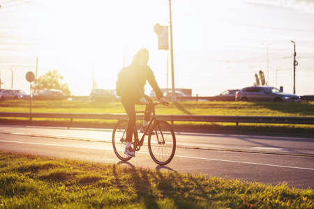 Riga, Latvia - October 6, 2021: people, travel, tourism, leisure and lifestyle - happy young hipster man with fixed gear bike and backpack on city street, sun effectのeditorial素材