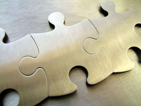 Three metallic jigsaw pieces on a steel backgroundの写真素材