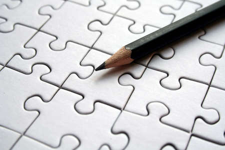 Black pencil on white jigsaws backgroundの写真素材