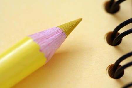 Yellow pencil on yellow notepad with black spiralsの写真素材