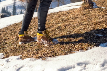 girl in yellow work boots on snow, and legs in black pantsの写真素材