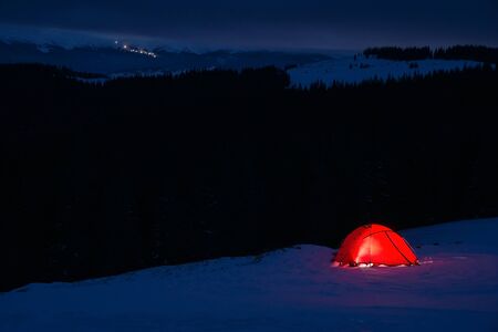 red tent on the snow at night in winter mountainsの写真素材