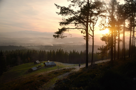 Sunrise above the high mountain foggy valley with old wooden houses on a hillの写真素材