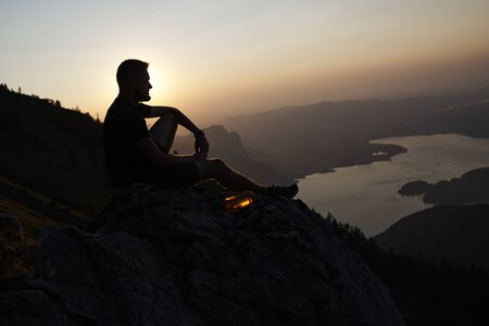 loneliness. Man sit on the rock and watching at lake in valley. Tyrol, Austriaの写真素材