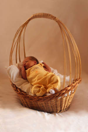 A newborn baby in a wicker basket lined with white materialの写真素材
