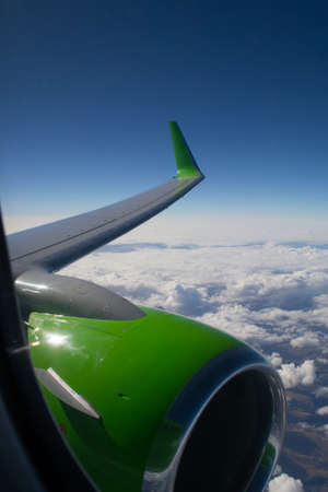 View of wing and engine in flight over cloudsの写真素材