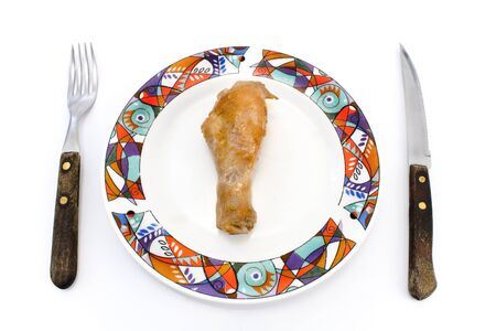 Roasted chicken leg on plate with fork and knife isolated on whiteの写真素材