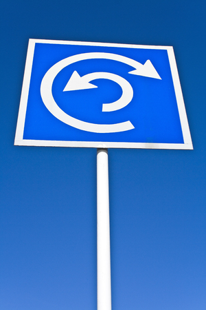 Roundabout sign over blue skyの写真素材