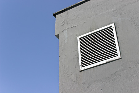 Vent window on gray concrete wall with blue skyの写真素材