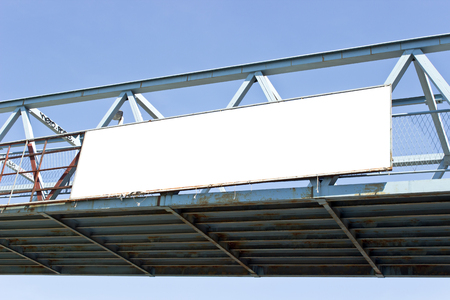 Billboard on pedestrian bridge  over blue skyの写真素材