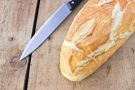 Homemade bread with kitchen knife on wooden background