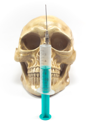 Syringe over human skull isolated on whiteの写真素材