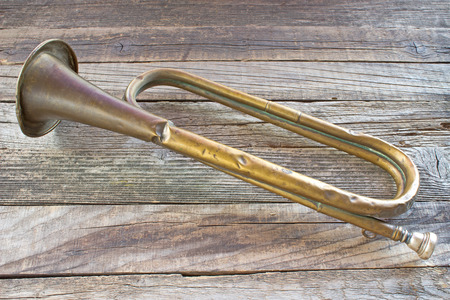 Old broken army trumpet on wooden background