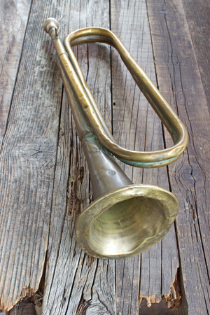 Old broken army trumpet on wooden background