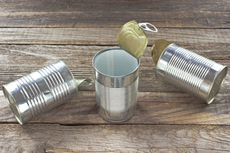 Three open empty tin can on wooden background