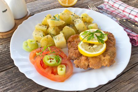 Wiener schnitzel with potatoes in plate on tableの写真素材
