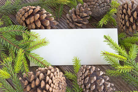 Merry Christmas card with pine tree needles and cones on wooden background の写真素材