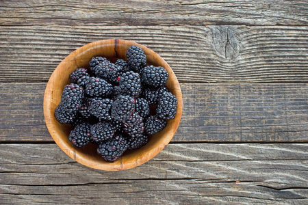 Blackberry fruit in  bamboo bowl on wooden backgroundの写真素材