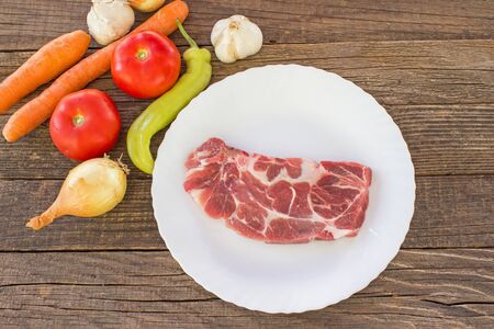 Raw pork meat chop with vegetable on wooden tableの写真素材