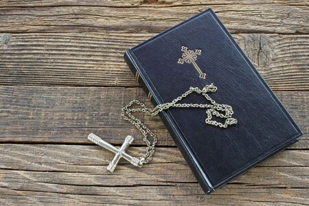 Holy bible with silver cross on wooden background