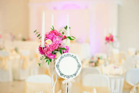 Nice flowers with candles in vase on table in restaurant in wedding dayの写真素材
