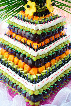 Pyramid with fruits and sweets on the white table on the wedding banquetの写真素材