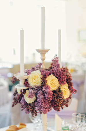 Nice flowers with candles in vase on table in restaurant in wedding dayの写真素材