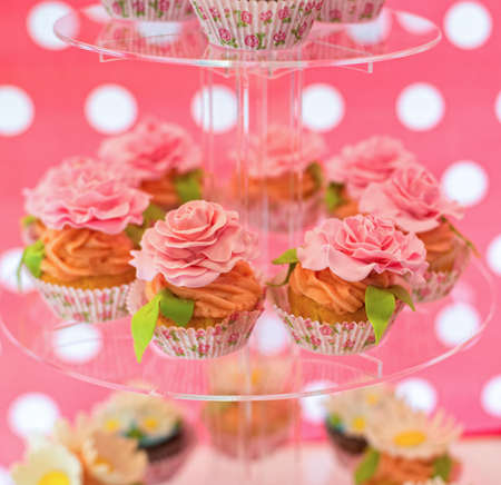 Delicious cupcakes with cream roses on the glass plateの写真素材