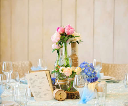 Beautiful tender flower arrangement on the table with menu and table number for an event, party or...