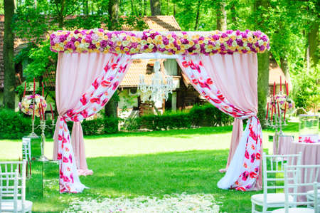 Pink wedding arc with roses and peonies like decoration for elegant wedding ceremony in the gardenの写真素材