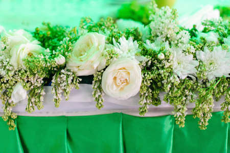 flower composition of white roses and lilac on the green table for event or wedding celebrationの写真素材
