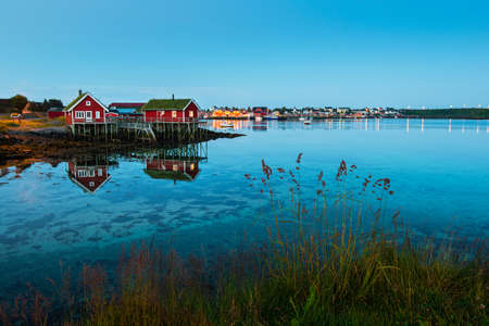Amazing view of Lofoten islands: village Reine with red houses near clear green water and beautiful...