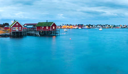 Scenic landscape on Lofoten islands, Reine with typical red fishing hut with grass on the roof near...