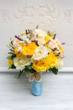 Beauty of colored flowers. Bridal accessories. Close-up bunch of florets. Details for marriage and for married couple. Wedding bouquet with roses on the white backgroundの写真素材