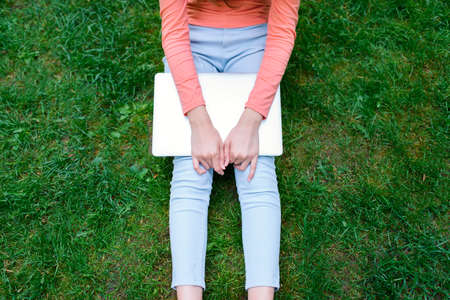 Beautiful young blonde female student sitting in the park with a laptop computer.の写真素材