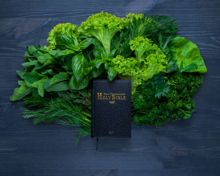 Composition with salad and bible on wooden background