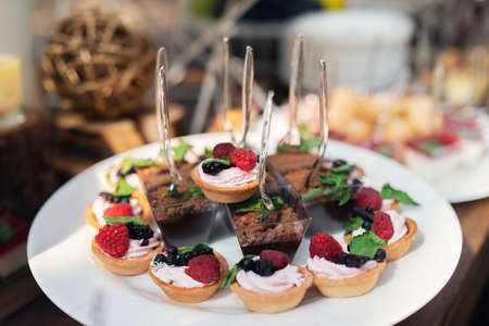 Tasty sweets on a brown rustic wooden banquet table. Summer wedding in the forest. Banquet table....