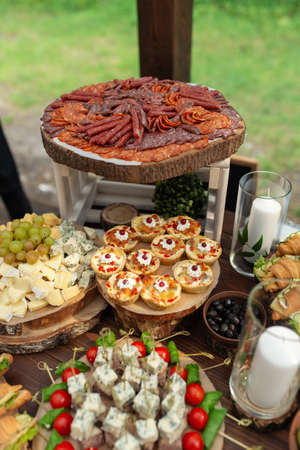 Tasty meals on a brown rustic wooden banquet table. Summer wedding in the forestの写真素材