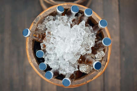 Bottles of refreshing cold drink in wooden bucket full of iceの写真素材
