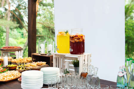 Glass jars of lemonade on wedding candy bar. Catering. Drinks on wedding party. Summer wedding in the forest. Elegant wedding table arrangementの写真素材