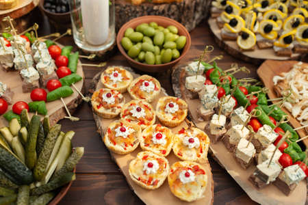 Tasty meals on a brown rustic wooden banquet table. Summer wedding in the forest
