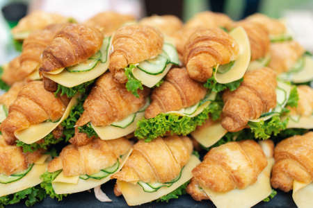 Delicious croissants sandwiches with fresh cucumber, cheese, hard boiled egg and salad. Closeup viewの写真素材