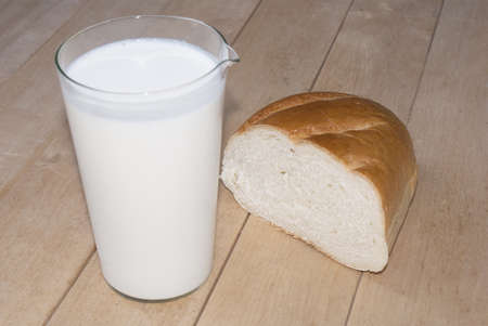 Glass fresh milk and bread over boards backgroundの写真素材