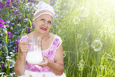 Adult female with big glass jug fresh milk on a natureの写真素材
