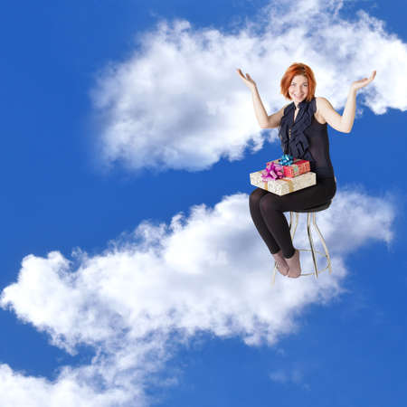  Happy red-haired girl with gifts in cloud dreams on a chairの写真素材